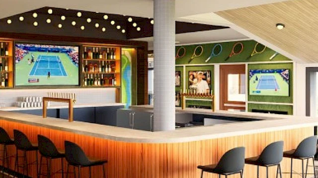 A stylish indoor bar area with tennis-themed decor, multiple TVs showing tennis matches, and seating for guests to relax.