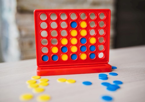 A Connect Four game in progress with blue and yellow discs on a table, featuring a red vertical grid.