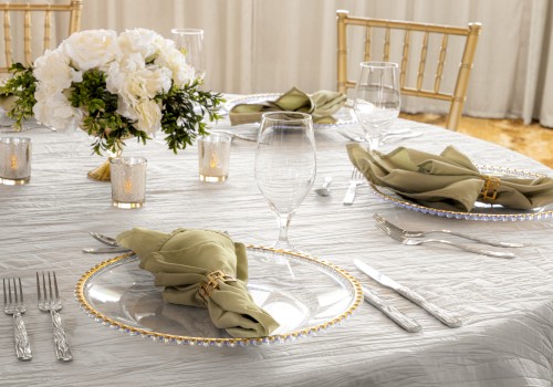 A elegantly set table with plates, folded napkins, glassware, candles, and a floral centerpiece.