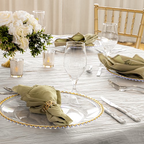 A elegantly set table with plates, folded napkins, glassware, candles, and a floral centerpiece.