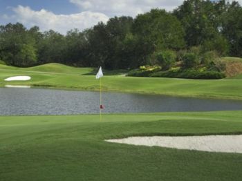 A serene golf course with a flag, sand bunker, lush greens, and a