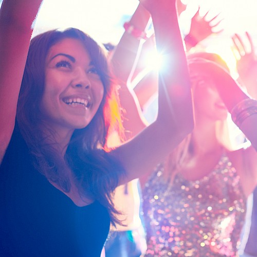 People dancing and having fun at a lively party with colorful lighting.