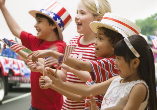 Kids celebrating at an outdoor event with patriotic hats, flags, and red, white, and blue clothing, likely for Independence Day.
