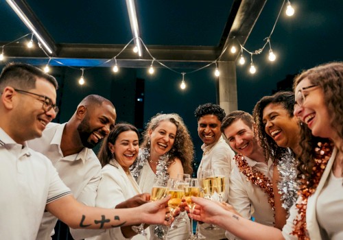 A diverse group of friends celebrating together with drinks at an outdoor party under string lights at night.