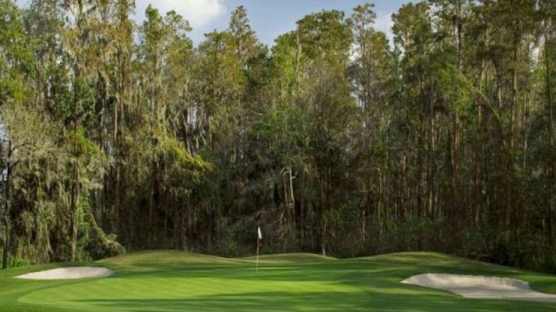 A serene golf course with a lush green, sand bunker, flagstick, and