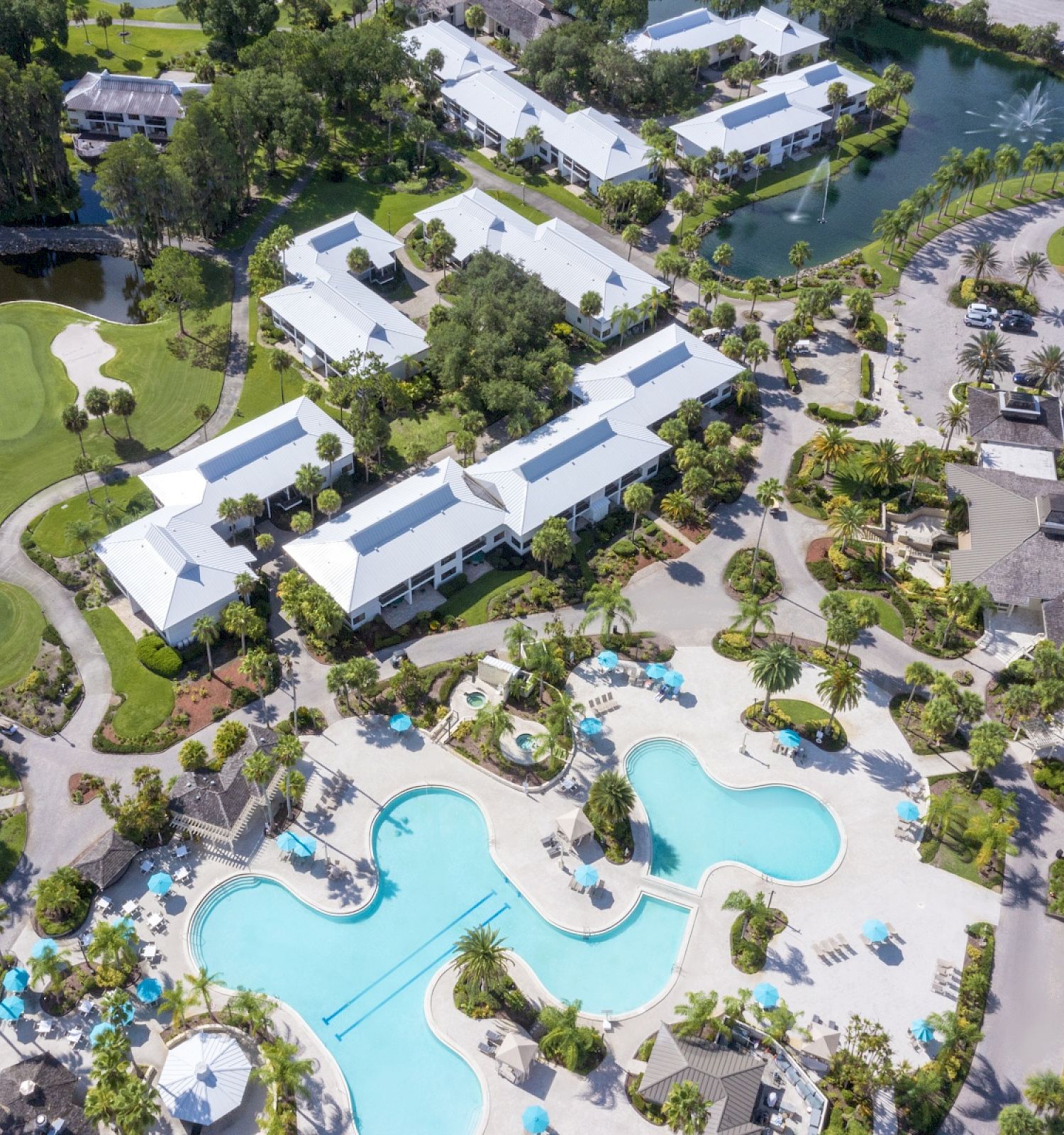 Aerial view of a resort with swimming pools, golf courses, and lakes.