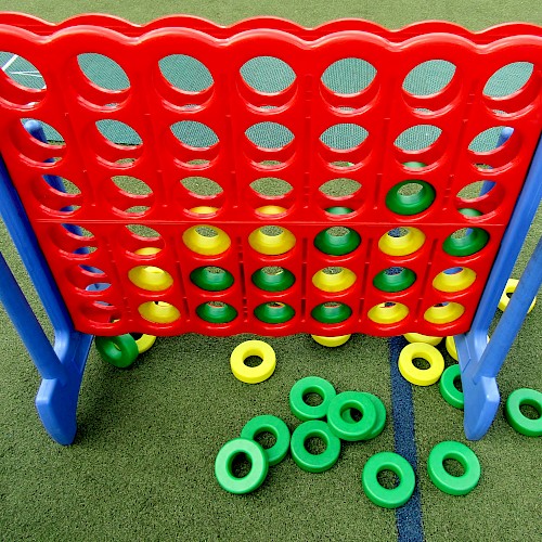 Large Connect Four game with red/yellow discs; some on the ground.
