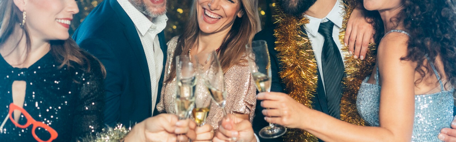 A group of people dressed in festive attire are happily toasting with champagne in a celebration setting.