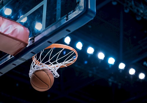 A basketball going through a hoop under stadium lights, viewed from below the basket.
