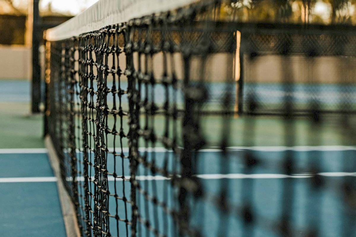 A close-up view of a tennis net on a court, with blurred background and clear focus on the net's texture.