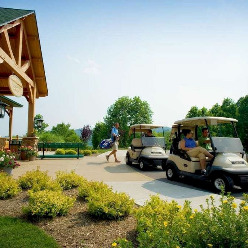 The image shows a golf course entrance with a few people, some in golf carts, and one person walking with a golf bag under clear skies.
